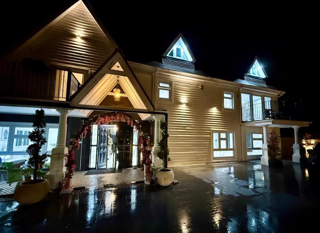 The entrance on a party night — the floral arch lit, doors open