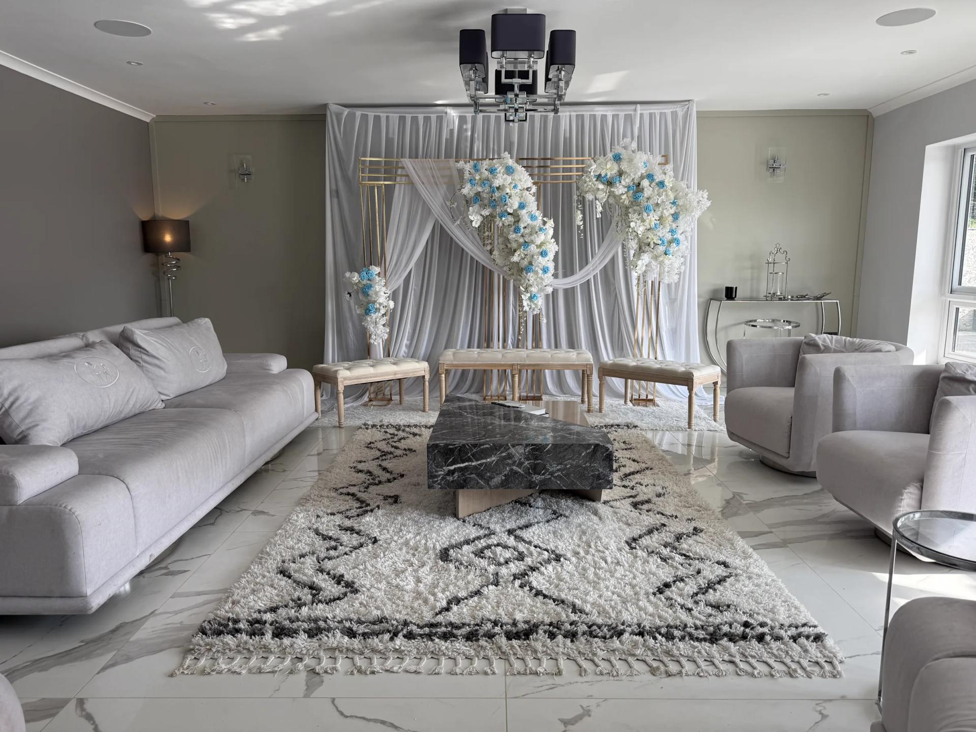 Lounge dressed for wedding ceremony — floral arch, gold frame, white drapes