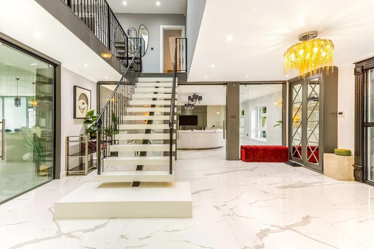 The entrance hall — marble stone table, open fireplace, sweeping staircase