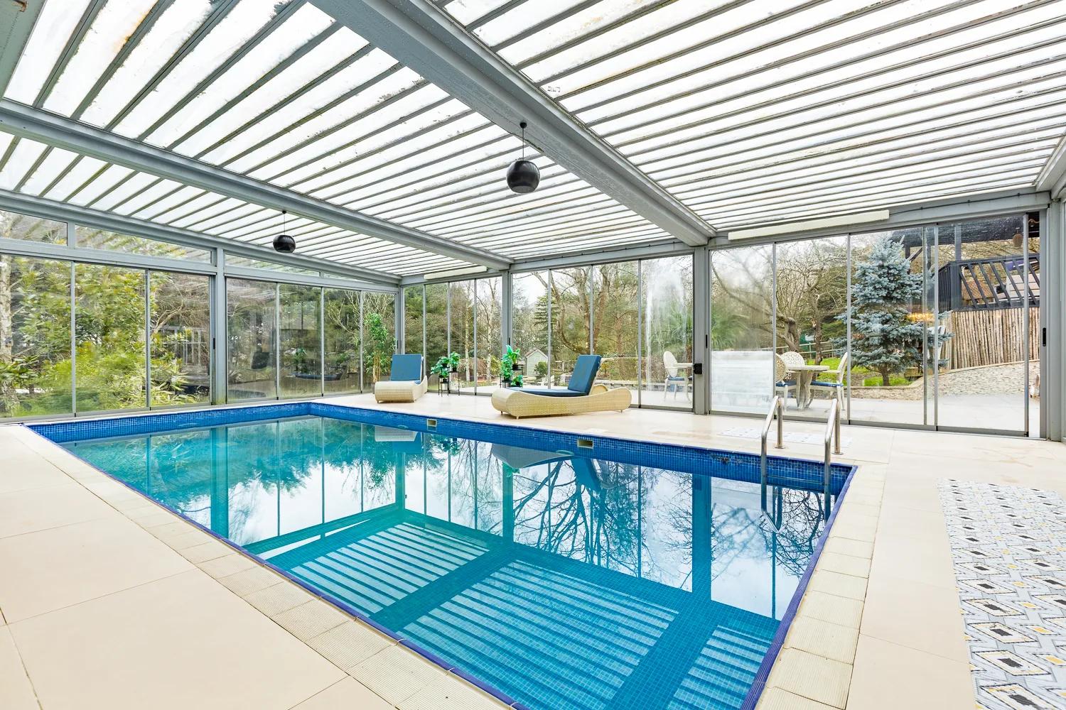 The pool under its louvred glass roof, blue mosaic tiles