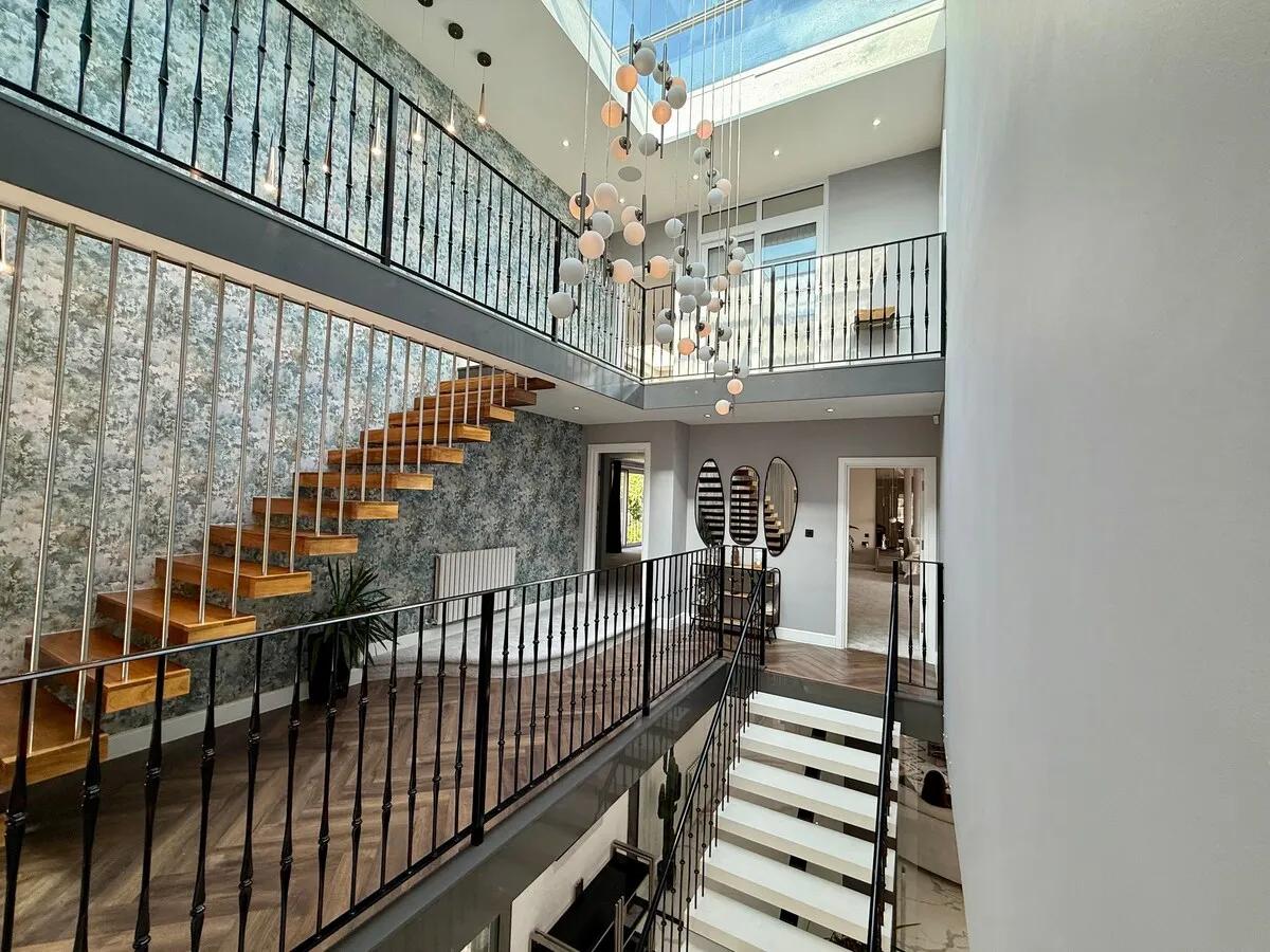 The staircase and upper landing — warmly lit, herringbone floor